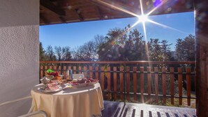 An outdoor patio with a table set for dining, a chair, and a wooden fence in the background. - Villa La Verbanina Private Garden (Ghiffa)