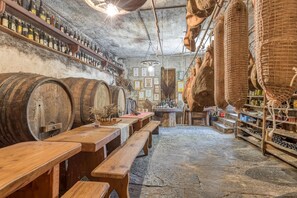 A rustic cellar with wooden barrels, wooden tables, and shelves stocked with bottles. - Countryside House Leila (Sezana)