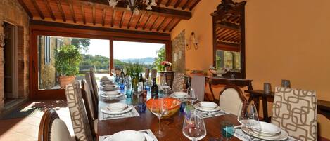 A dining area with a wooden table set for a meal, surrounded by chairs, and a view of the outdoors.