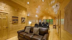 A cozy log cabin interior with a leather sofa, wooden walls, and ceiling lights. - Four Seasons Lodge #4219 (Pigeon Forge)