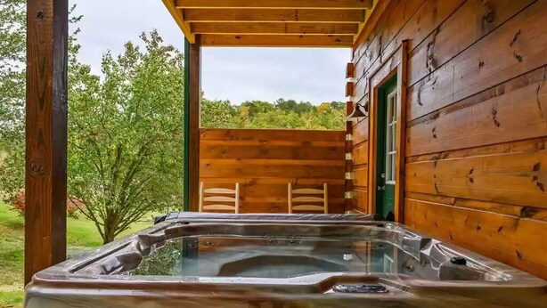 A wooden cabin with a hot tub and outdoor seating. - Four Seasons Lodge #4219 (Pigeon Forge)