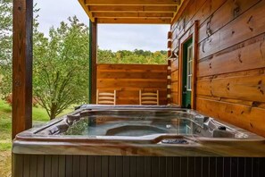 A wooden cabin with a hot tub and outdoor seating. - Four Seasons Lodge #4219 (Pigeon Forge)