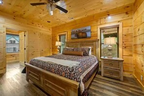 A wooden cabin bedroom with a bed, nightstands, a ceiling fan, and a painting on the wall. - Four Seasons Lodge #4219 (Pigeon Forge)