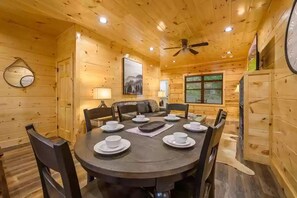A wooden cabin with a round dining table set for six, surrounded by chairs. - Four Seasons Lodge #4219 (Pigeon Forge)
