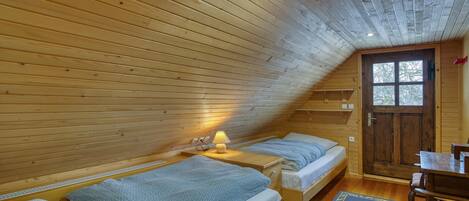 A cozy cabin with two wooden beds, a small table, and a door leading outside.
