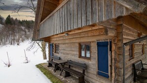 A rustic log cabin with a stone-paved porch, a bench, and a small table. - Chalet Kupljenik Near Bled Lake (Bled)