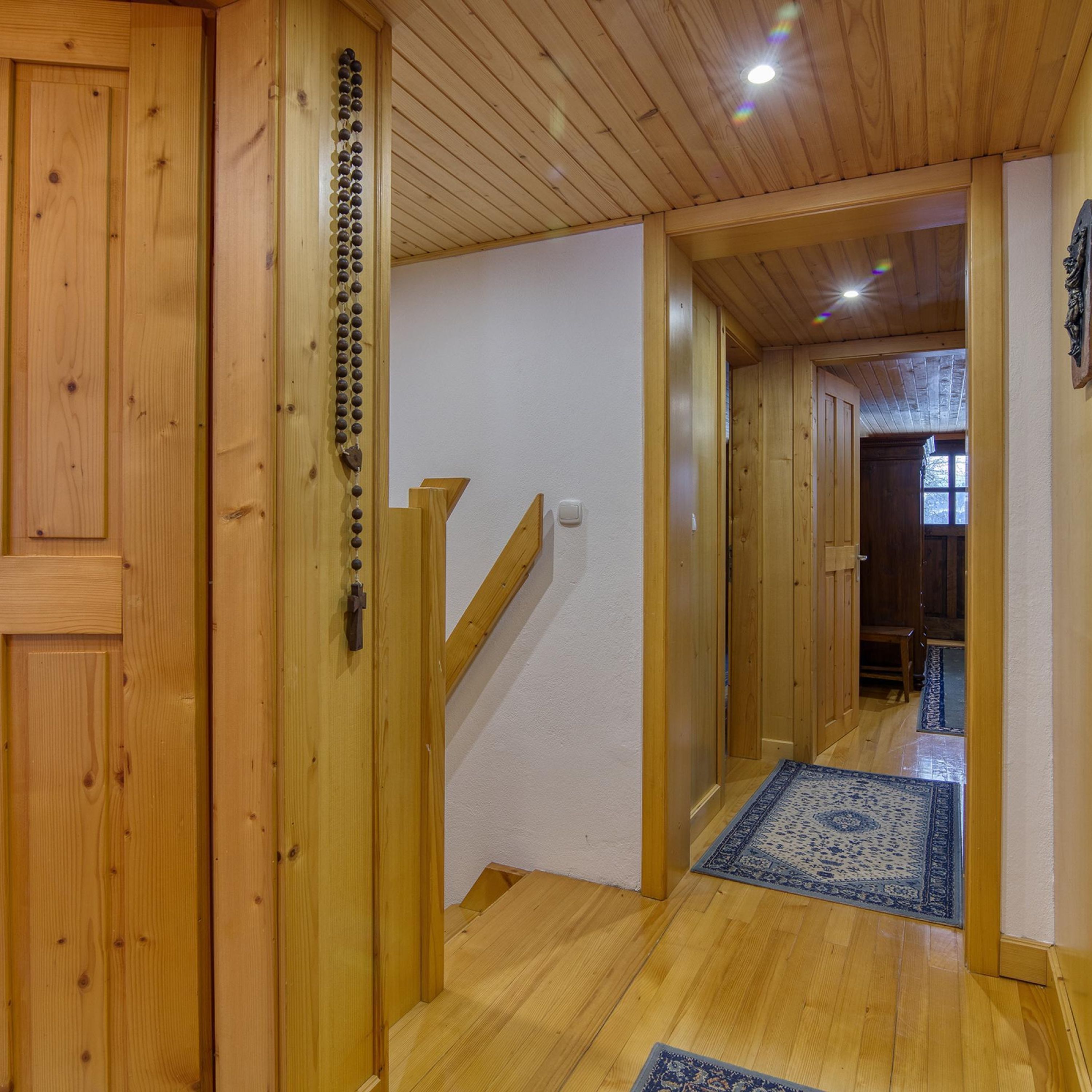 Un intérieur en bois avec un escalier, des murs en bois et un tapis à motifs sur le sol.