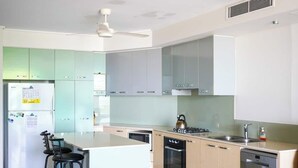 Een moderne keuken met lichtgroene kasten, een wit kookeiland, een ingebouwde oven en een vaatwasser.