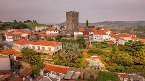 A historic town with a prominent tower, traditional buildings with red-tiled roofs, and a lush green landscape. - Douro Mool Guest House (Lamego)