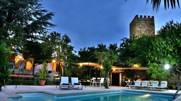 A swimming pool with lounge chairs, surrounded by greenery and a stone tower. - Douro Mool Guest House (Lamego)