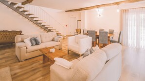 A spacious living room with a staircase, a dining area, and a large window. - Douro Mool Guest House (Lamego)