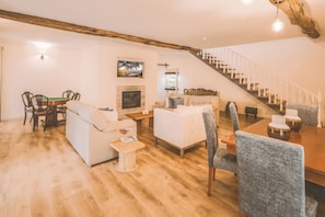 A spacious living room with a fireplace, a dining area, and a staircase. - Douro Mool Guest House (Lamego)