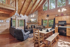 Un interior de cabaña acogedor con chimenea, una mesa de comedor de madera y un marco de piedra para la chimenea.