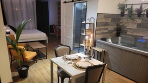 Un espace de vie compact comprenant un coin repas, une kitchenette et un lit.