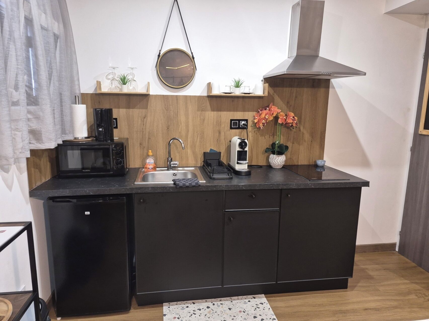 Et kompakt køkken med mikroovn, brødrister, vask og kaffemaskine.