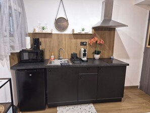 Et kompakt køkken med mikroovn, brødrister, vask og kaffemaskine.