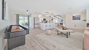 Un salon moderne avec un baby-foot, une table basse et une cuisine en arrière-plan.