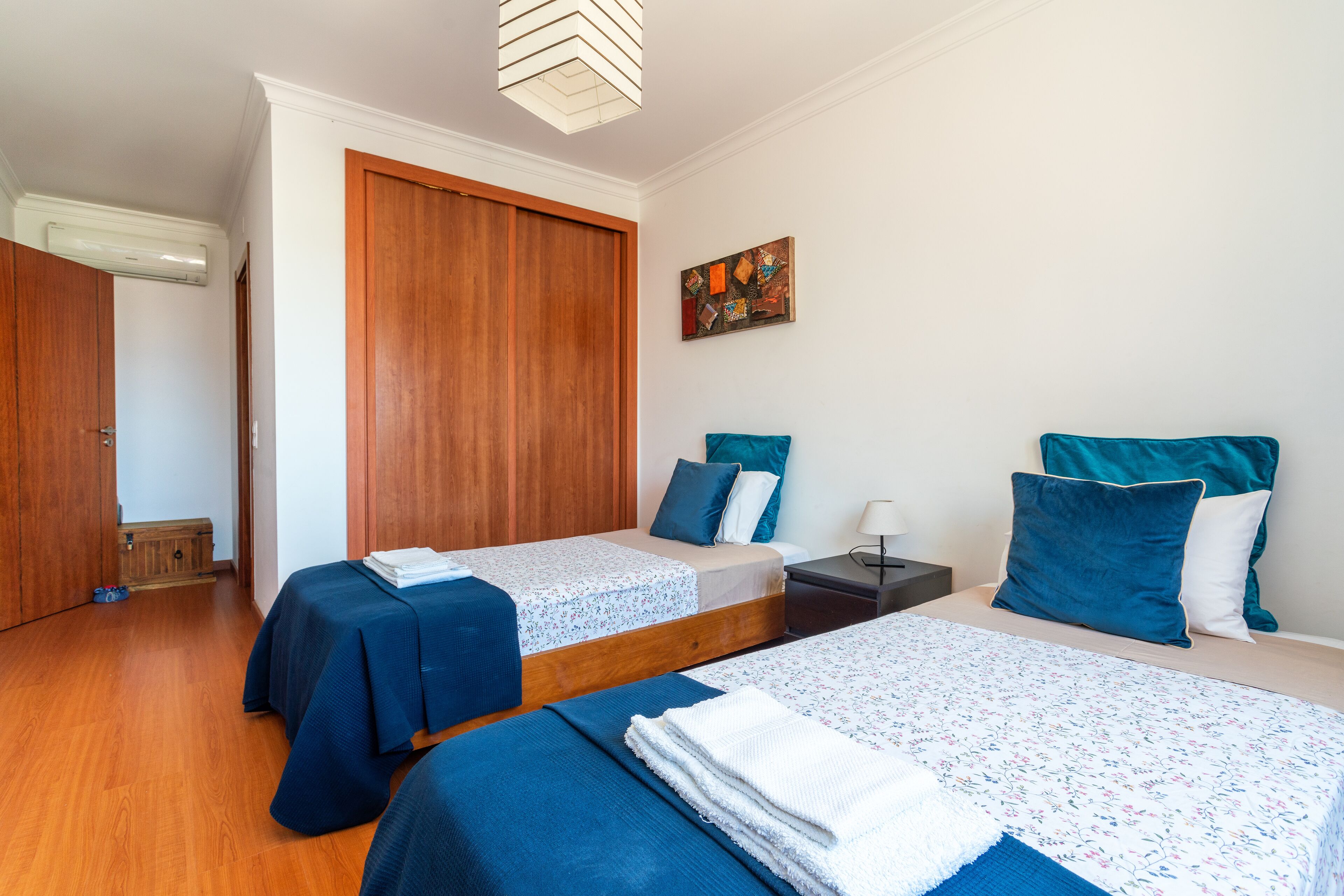 Ein Hotelzimmer mit zwei Betten, Holzboden, einem Kleiderschrank und einem Bild an der Wand.
