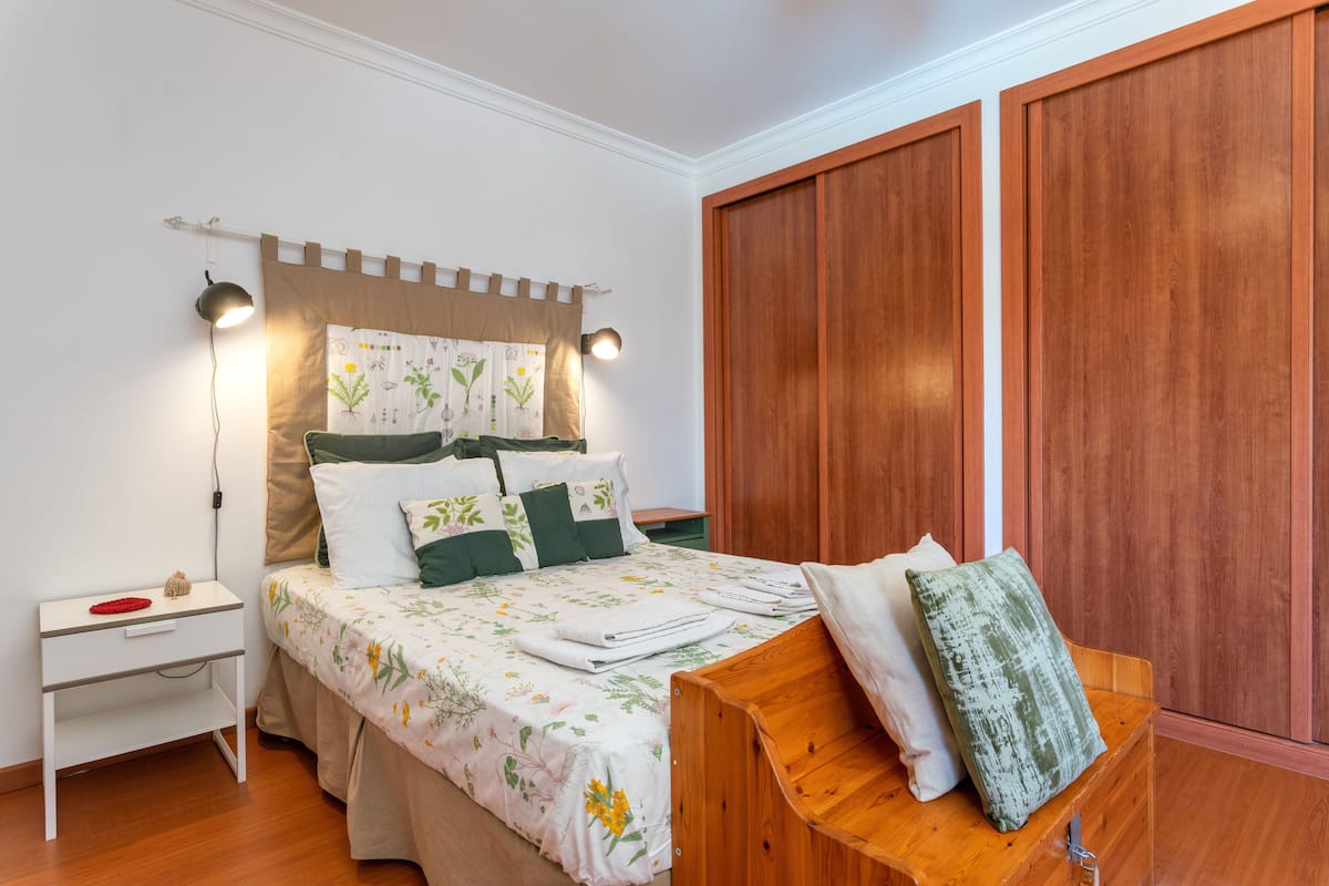 Une chambre à coucher avec un lit, une table de chevet, une lampe et une armoire en bois.