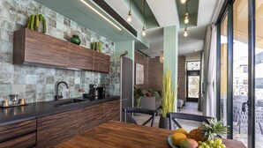 A modern kitchen with a wooden countertop, a sink, and a dining area with a table set for a meal. - The Shell House (Tel Aviv)