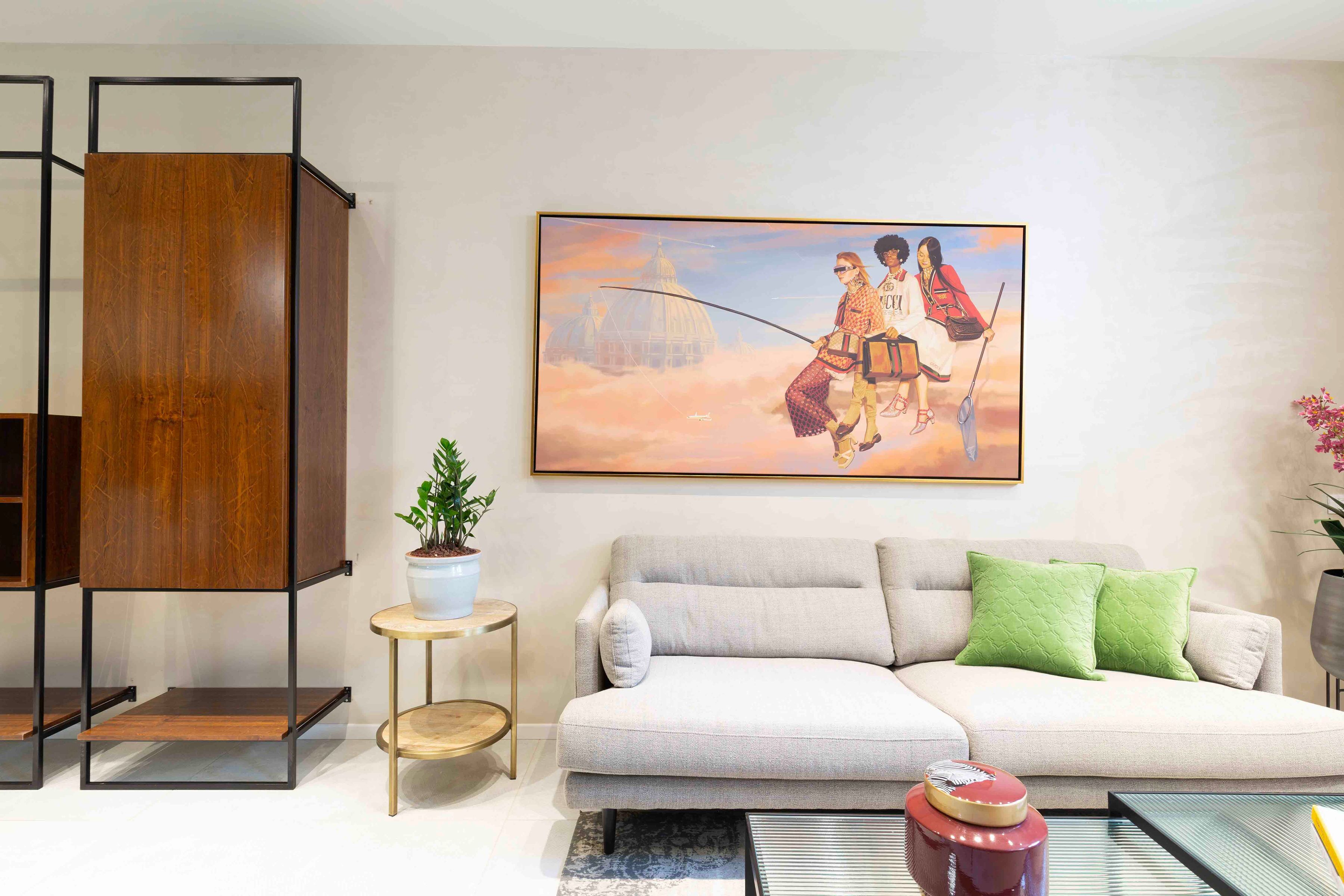 Un salon avec un canapé, un tableau, une plante en pot et une table basse.