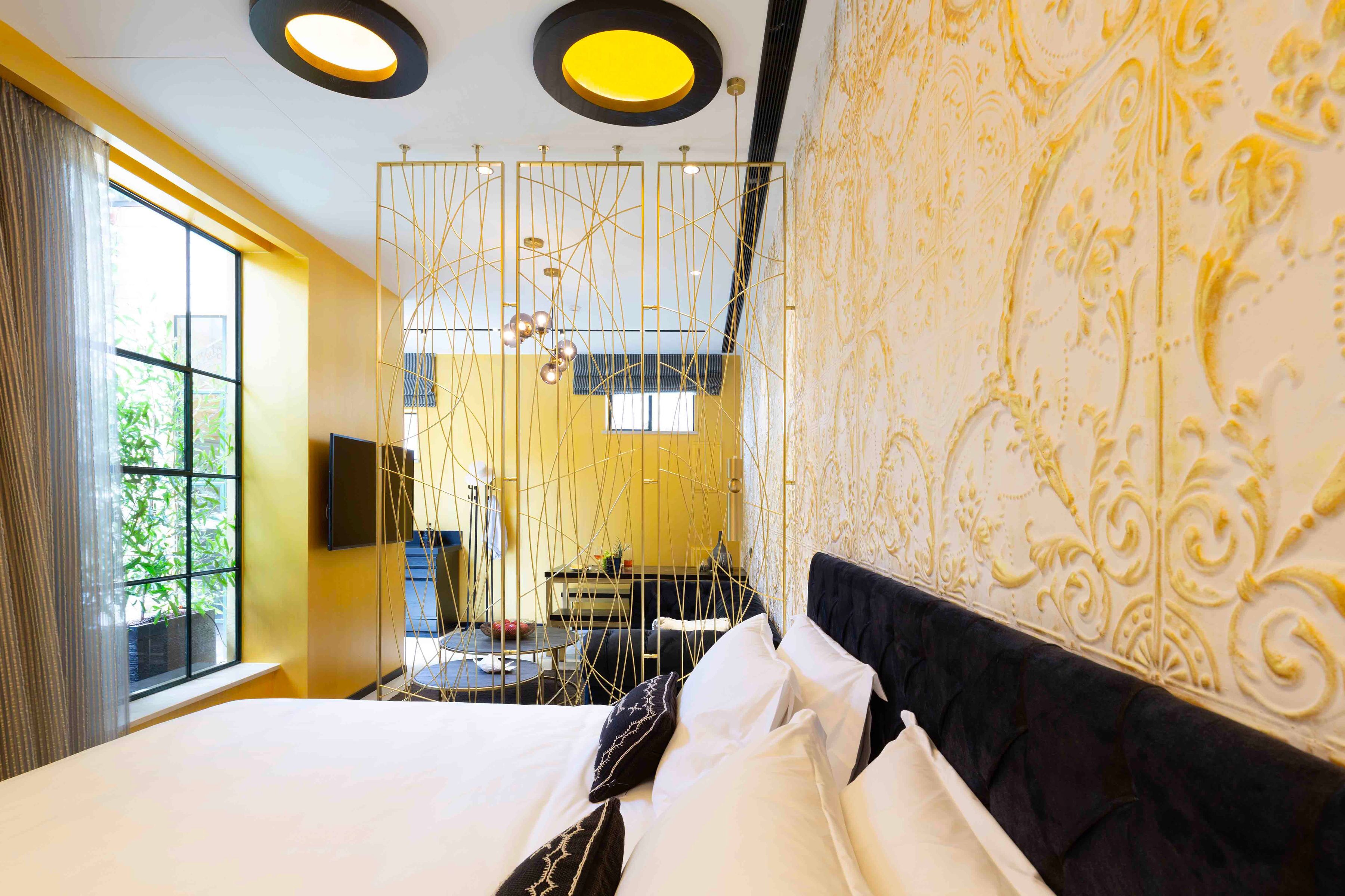 A hotel room with a large bed, a view of the outdoors, a decorative wall, and a unique ceiling design.