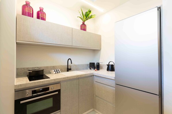 A modern kitchen with a built-in oven, a sink, and a refrigerator. - The Shell House (Tel Aviv)