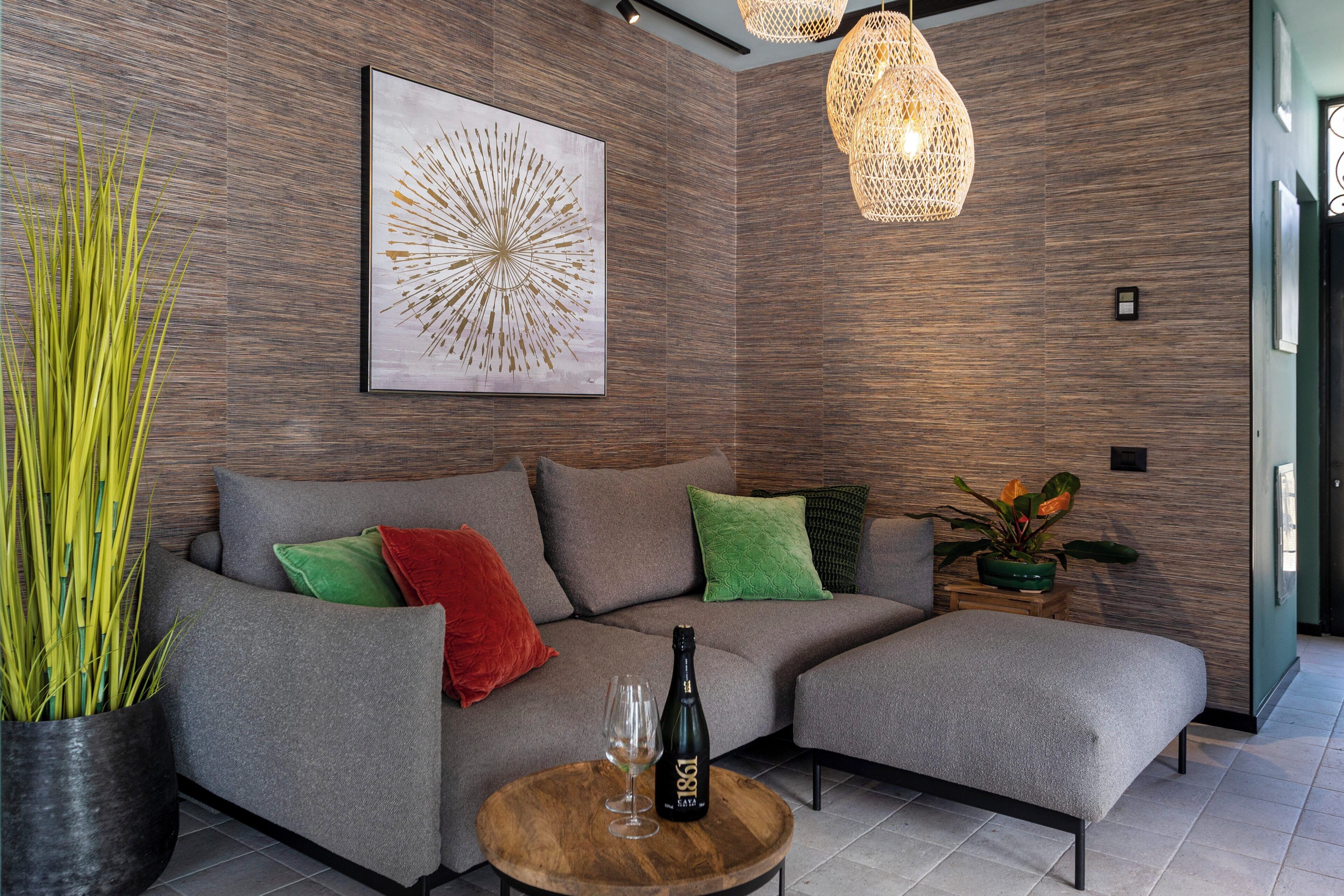 A modern living room with a sectional sofa, a wooden coffee table, a bottle of champagne, and a large abstract painting on the wall.