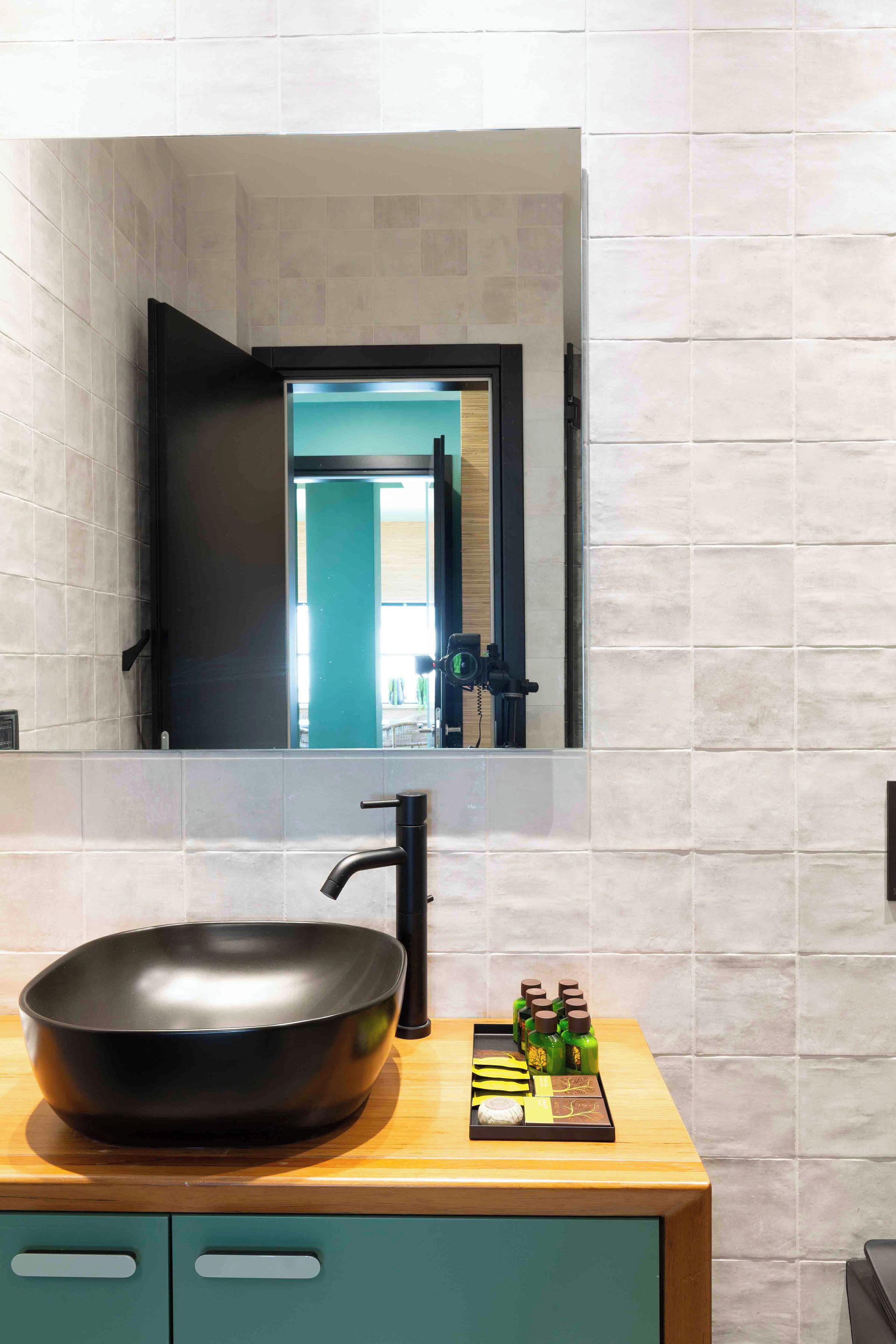 A modern bathroom with a large black basin, a faucet, and a mirror above it.