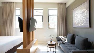 Una habitación de hotel moderna con cama, sofá, televisión y obras de arte.