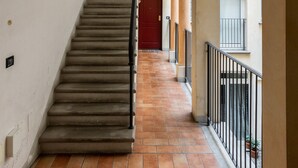 Ein Korridor mit einer Treppe zu einer roten Tür, gefliestem Boden und Holzbalken an der Decke.