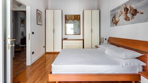 Ein Schlafzimmer mit einem hölzernen Bett, weißer Bettwäsche, einem Holz-Kopfteil, einem großen Spiegel und einem Bild an der Wand.