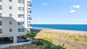 Edifício moderno com vista para a praia, com várias varandas e área de estacionamento.