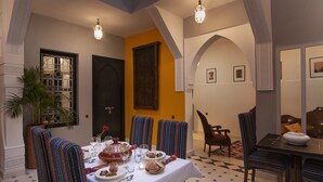 A dining area with a table set for a meal, chairs with striped upholstery, and a potted plant. - Riad Mylaya (Marrakech)