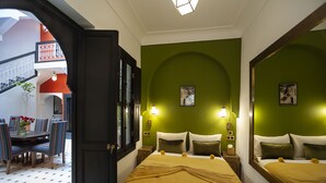 A hotel room with a green wall, two beds, a dining area with striped chairs, and a staircase. - Riad Mylaya (Marrakech)