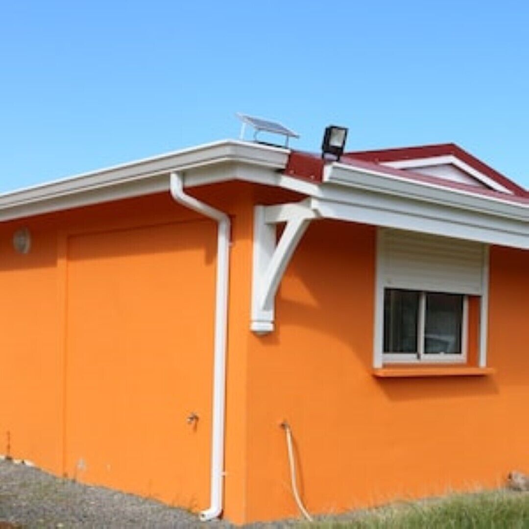 Ein Haus mit orangefarbener Fassade, weißem Zierdekor und rotem Dach.
