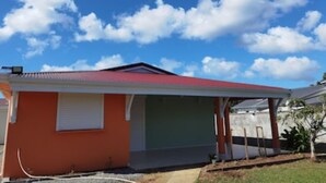 A single-story house with a red roof and a garage door. - House well located in La Jaille in the center of Guadeloupe (Baie-Mahault)