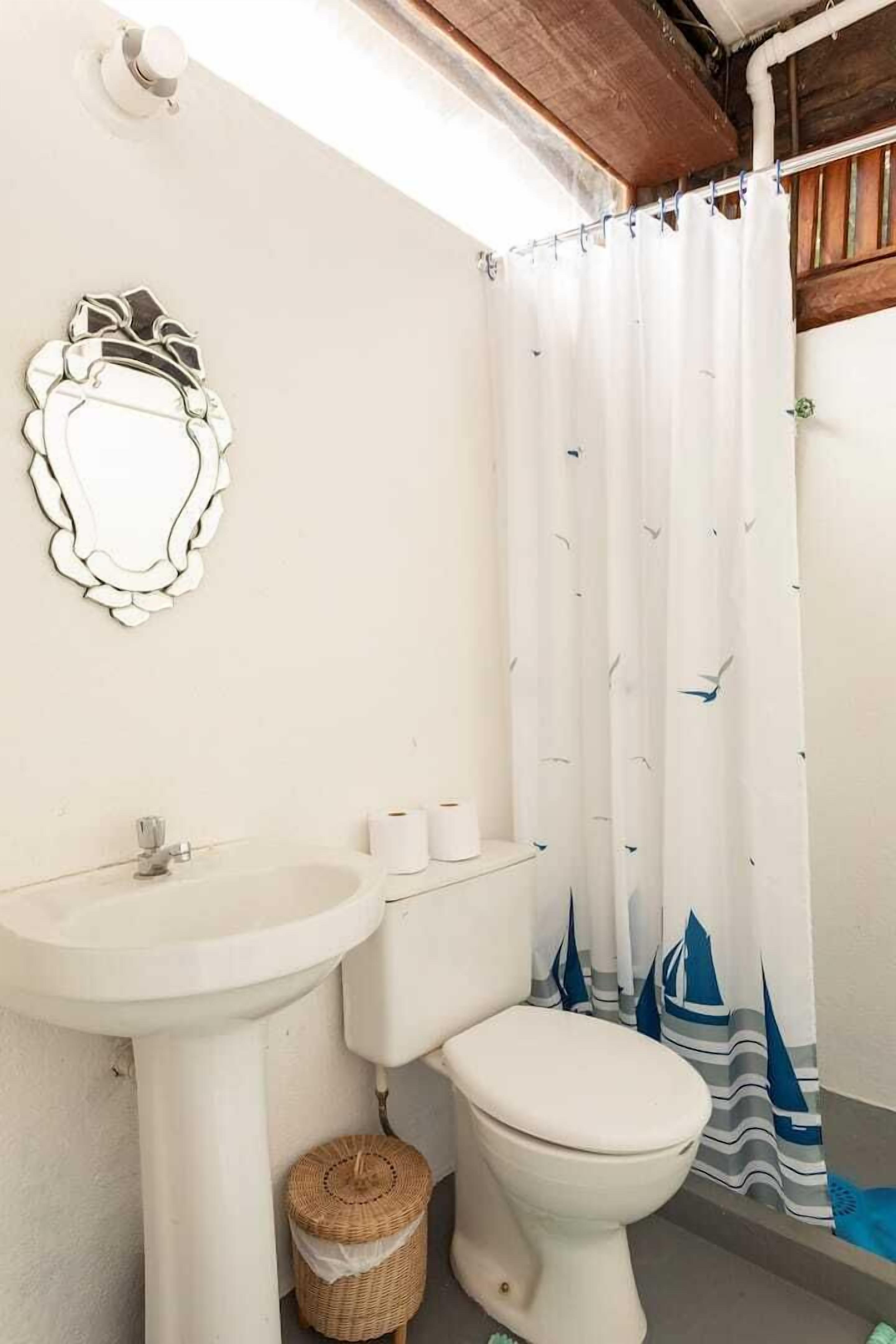 A bathroom with a white sink, toilet, and a shower curtain with a nautical pattern.