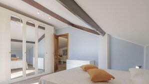 Quarto com cama grande, guarda-roupa e porta deslizante que dá para outro cômodo.