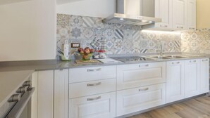 Uma cozinha moderna com armários brancos, uma pia de aço inoxidável e um revestimento de parede estampado.