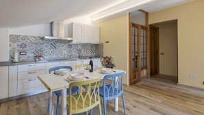 Cozinha compacta com armários brancos, backsplash em azulejo e área de jantar com mesa e cadeiras.