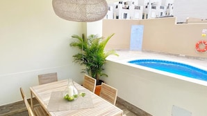 Een eetgedeelte met uitzicht op het zwembad, met een tafel en stoelen, een hangende lamp en een potplant.