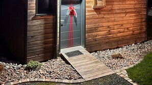 A wooden cabin with a door adorned with a red ribbon, a small window, and a porch area.