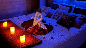 A bedroom with a wooden headboard, a bed with a white comforter, red and white pillows, and a decorative swan.