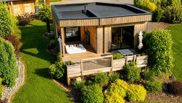 A modern house with a hot tub, wooden deck, and a well-maintained garden.