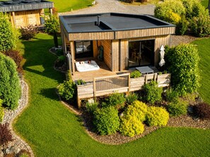 A modern house with a hot tub, wooden deck, and a well-maintained garden. - Luxury Chalet l'écureuil with private spa at Nature Cottage Vosges (Anould)