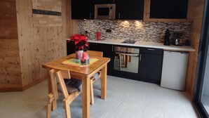 A modern kitchen with wooden cabinetry, a built-in microwave, and a small refrigerator.