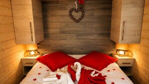 A bed with red and white bedding, heart-shaped decorations, and a heart-shaped garland on the wall. - Nature Cottage Vosges Le Renard (Anould)