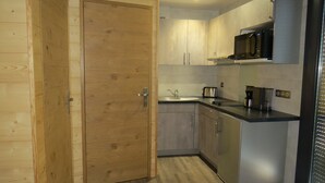 A compact kitchen with wooden cabinetry, a built-in microwave, and a sink. - Nature Cottage Vosges Le Renard (Anould)