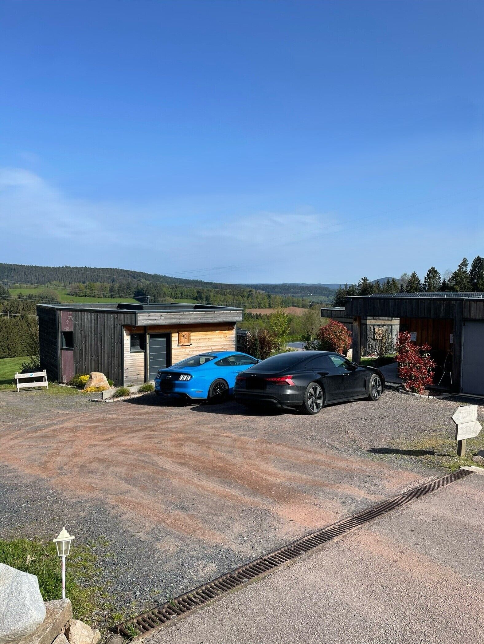 En moderne bygning med grusvej og to parkerede biler.